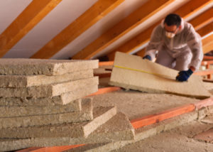 Thermal insulation of a building - mineral wool panels stack with man measuring in the background